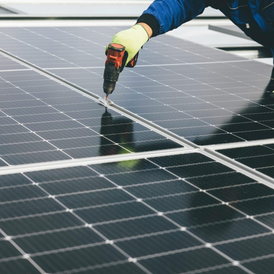 A person working on solar panels with a yellow glove.